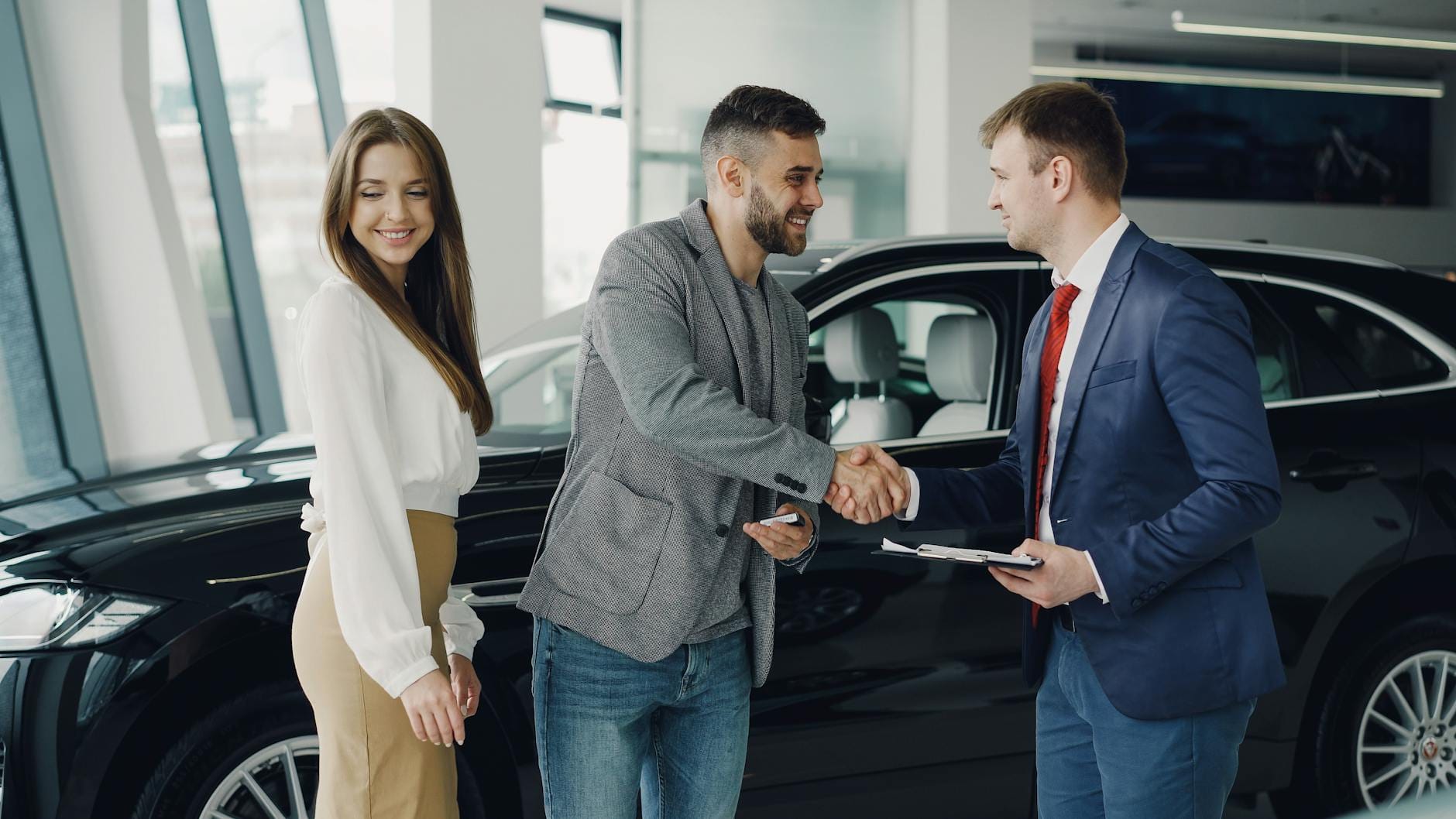 Kupujący ściska dłoń sprzedawcy w komisie samochodowym