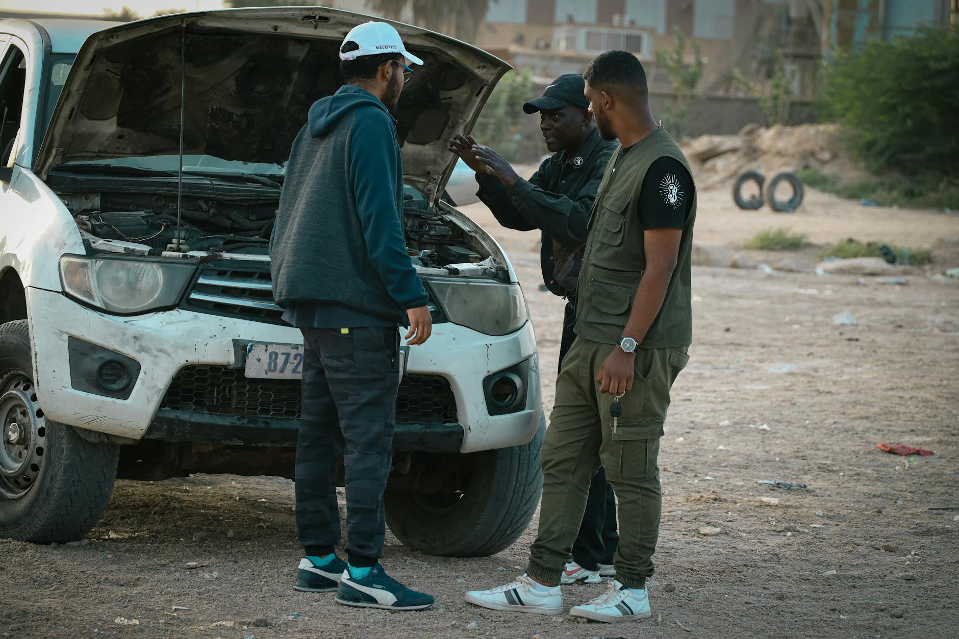 Trzech mężczyzn ogląda silnik samochodu i rozmawia o naprawie