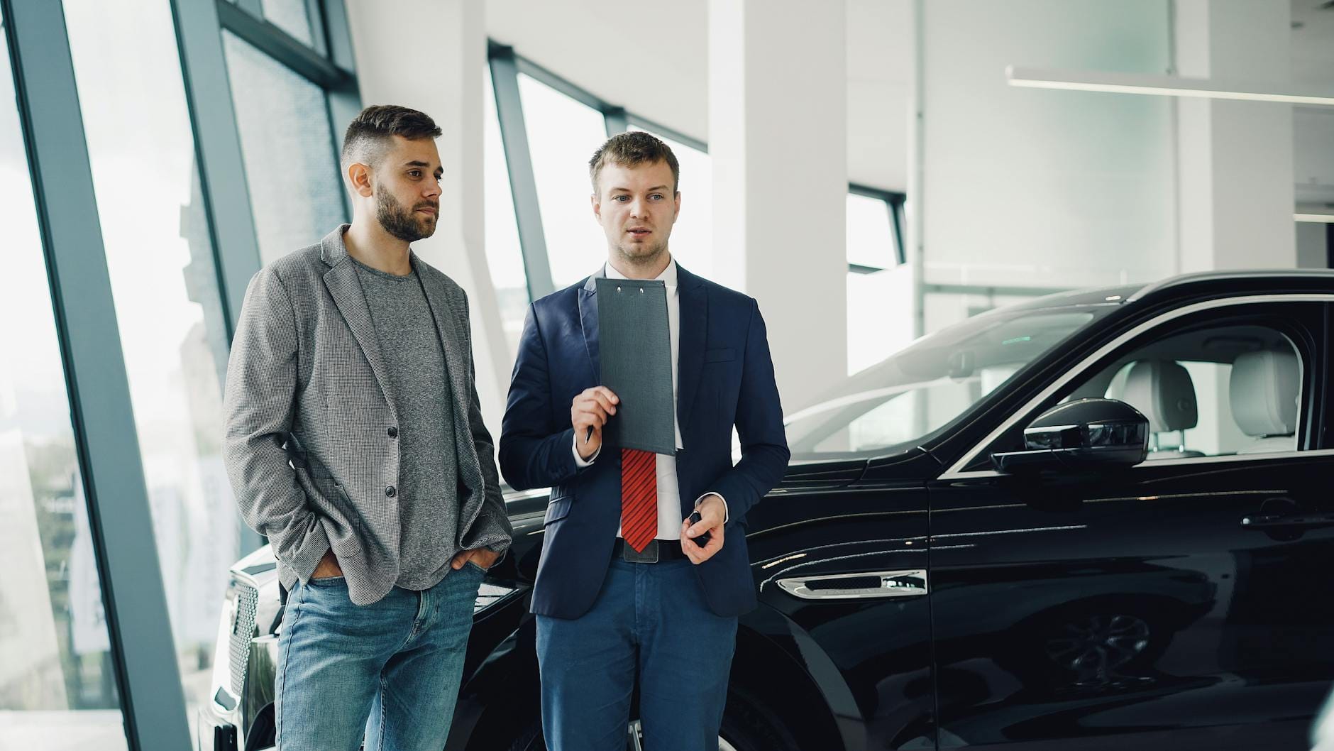 Dwóch przedsiębiorców omawia zakup auta w salonie samochodowym