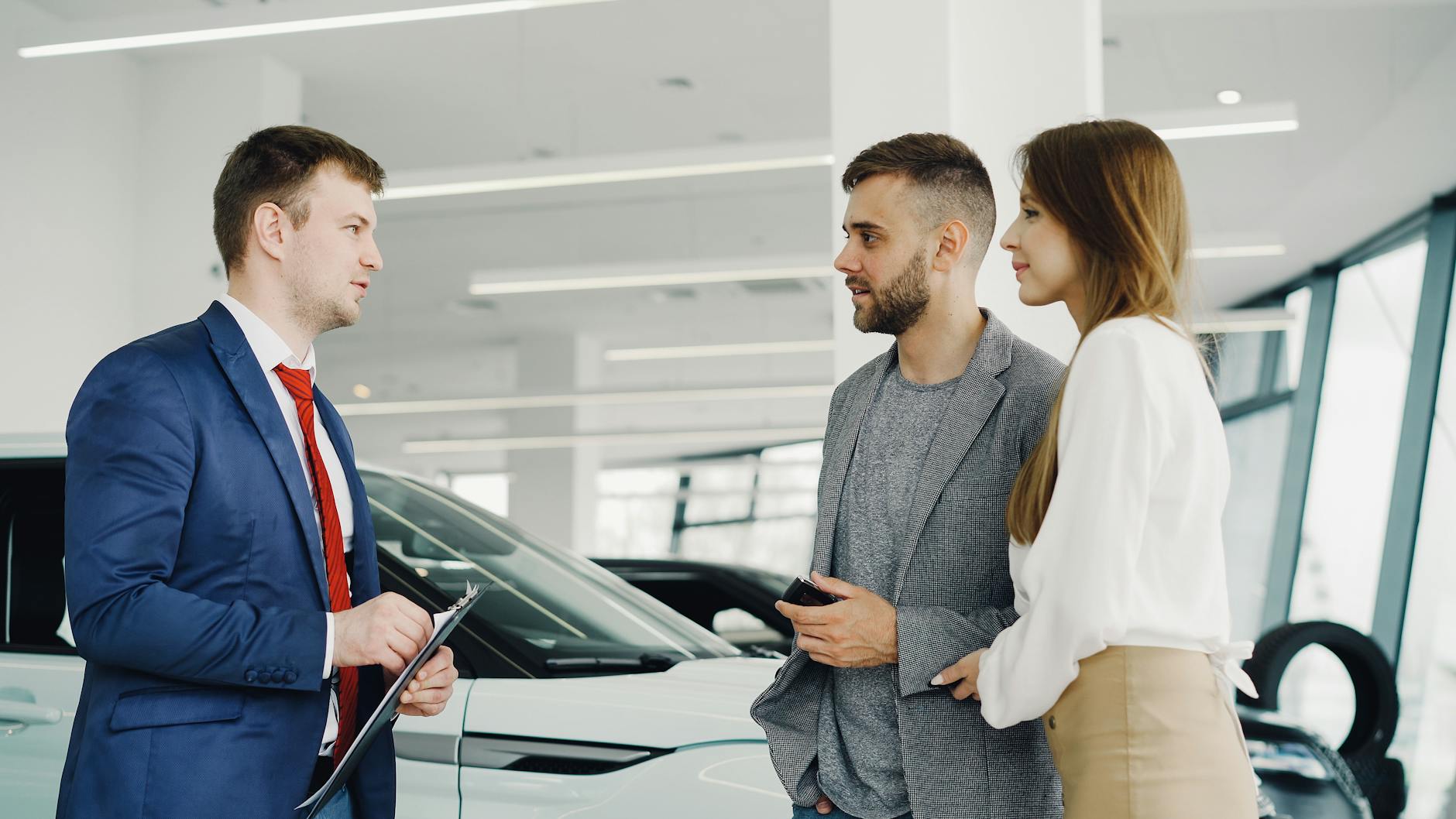 Sprzedawca pokazuje parze luksusowe auto w salonie samochodowym